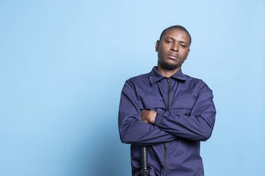 Stüdyoda kollarını kavuşturarak poz veren kendine güvenen güvenlik ajanının portresi. Koruyucu üniformasını gururla ve özveriyle giyiyor. Güvenlik önlemleri üzerinde çalışan yetenekli bir koruma..