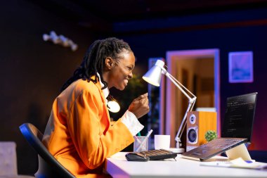 Yazılım programını başarıyla geliştirdikten sonra keyifli bir şekilde dizüstü bilgisayarında daktilo kodunu yazdı. Heyecanlı bir Afrikalı Amerikalı kadın yeni özellikleri uyguladıktan sonra heyecanlandı.