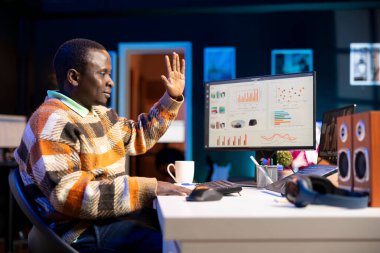 Afrika kökenli Amerikalı bir adam kişisel bilgisayar kullanarak muhasebe bilgisi hakkında konuşuyor. Çevrimiçi iletişim kuran ve aylık gelir dengesini inceleyen genç yetişkinler.