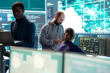Yüksek teknoloji ofisindeki bilgisayar ağında çalışan hükümet hackerları veri güvenliği ve siber operasyonlara odaklanıyorlar. Siber suçlar, veri koruması ve güvenli ortamda tehdit tespiti.