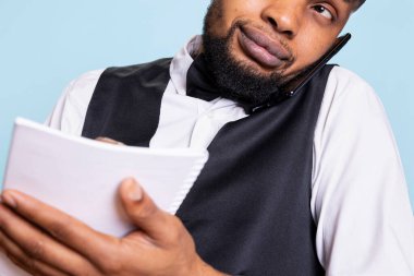 Resepsiyon personeli oda rezervasyonları için isim listesi hazırlıyor. Akıllı telefondan yapılan rezervasyonlar. Otel resepsiyonisti istenen konforlar için notlar alıyor..