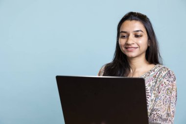 Kameranın önünde dizüstü bilgisayarında yazan başarılı bir günlük metin yazarı, işine ve serbest çalışmalarına odaklanmış. Kablosuz bilgisayarında çalışan, uzaktan kumandalı, gülen bir genç..