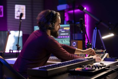 Müzik yapımcısı, kaydedilmiş şarkıları düzenlemek ve senkronize etmek için sanatsal post prodüksiyon üzerinde çalışıyor. Sanatçı söz yazarı, melodileri ve ses efektlerini değiştirmek için dijital ses çalışma istasyonu arayüzü kullanıyor.