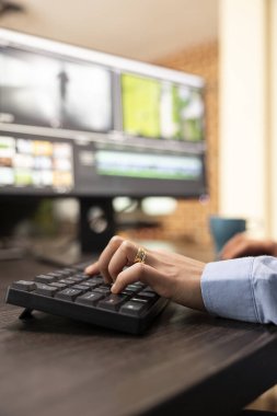 Ofis masasındaki bilgisayar klavyesini video düzenleme oturumunda kullanan birinin yakınlaşması. Çalışma istasyonunda oturan, film montajı ve görsel kalitesinin geliştirilmesi üzerine seçici bir odaklanma.