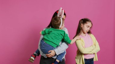 Pembe arka planla mücadele eden küçük çocuklar anneleri barışmaya ve çatışmayı bitirmeye çalışıyor. Küçük kardeşi tarafından rahatsız edilen genç bir kız, annesi arada kalmış. Kamera B.