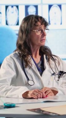 Kabinede sonuçları tartışmak için yaşlı bir erkek hastayla dikey video doktor toplantısı, X ışını görüntüleme ve sonuçlarını yorumlamak için gelişmiş teşhis araçları kullanarak, profesyonel sağlık hizmetleri