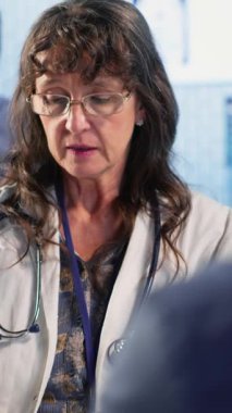 Dikey video sunucusu kadın, doktoruyla birlikte teşhis sonuçlarını değerlendiriyor, hastasına doğru sonuçları vermek için ileri teknoloji aletleri kullanıyor. Tıp endüstrisinde bakım yönetimi