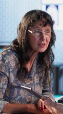 Dikey Video Genel Pratisyeni yaşlı kadın hastaya teşhis test sonuçları hakkında danışır, bir klinikte doğru rapor ve bakım yönetimi için tıbbi teknolojiden yararlanır. Sağlık hizmeti sağlayıcısı