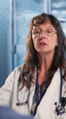 Dikey video sağlık uzmanı tıbbi uzmanlığını paylaşıyor ve MRI taramalarını erkek hastayla birlikte okuyor, doğru tanı için x ışını raporlarını inceliyor. Uzman tedavi planlarını tartıştı