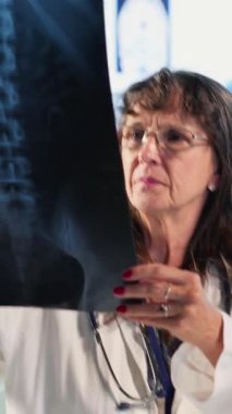 Dikey video kadın pratisyen yaşlı adama kötü haber veriyor, röntgen sonuçlarını okuyor ve tehlikeli bir teşhis koyuyor. Endişeli yaşlı bir hasta için tarama yap