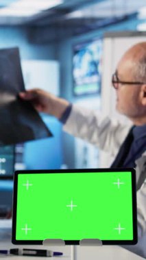 Dikey Görüntü kıdemli sıhhiyecisi, kadın hastasıyla konuşuyor. Yeşil ekranın yanında, sağlık sigortası konsültasyonunda. Hastalıklı yaşlı kadın doktorla tıp hakkında konuşuyor.