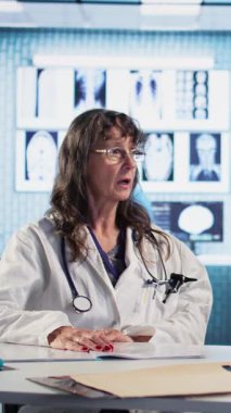 Dikey video eski bir hasta ve krom anahtar ekranının yanındaki kontrol uzmanı, reçeteli ilaç ve kurtarma planı hakkında konuşuyorlar. Genel pratisyen bir kadına tavsiye ve destek sunar