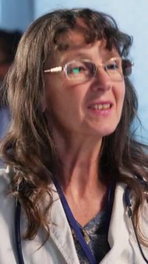 Dikey Videocu Kadın, rutin kontroller için bir erkek hastayı muayene ediyor. Klinikteki tedavi planı hakkında tartışıyorlar. Uzman, sigorta konusunda sağlık hizmetleri sunar. Kamera.