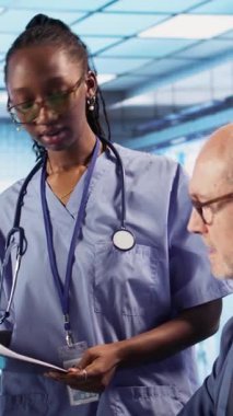 Dikey Video Uzmanı ve Afrikalı Amerikalı asistan, check-up 'ta hastalara tıbbi hizmetler sunuyor, tanı raporları ve tıbbi kayıtlar veriyor. Sağlık personeli sağlık sigortası testini güvence altına aldı