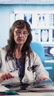 Dikey Görüntü kıdemli sıhhiyecisi hastaya hastalık teşhisinin kötü haberini veriyor. Ekranda x ışını görüntülemesi ile tıbbi konsültasyon. Sağlık sorunları ve profesyonel araştırmalar