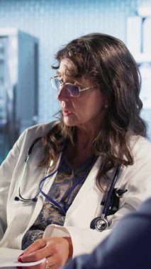 Hastayla istişarede bulunan dikey video kıdemli doktor kanser önleme ve erken teşhis hakkındaki radyografi taramalarını okuyarak kişiselleştirilmiş tedavi tavsiyeleri sunuyor. Risk faktörleri. Kamera.