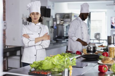 Lüks bir restoran mutfağında kadın aşçı mutfak tezgahında paslanmaz çelik aletler kullanarak güzel yemekler pişiriyor. Yemek hazırlama tekniklerinde ustalaşmak.
