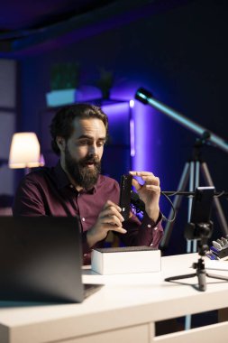 Teknoloji uzmanı akıllı telefon performansını değerlendiriyor, içeride kullanılan bileşenler hakkında konuşuyor, boks videosu çekiyor. Teknoloji çevrimiçi kanalında görüntülemek için cep telefonu paketlerini açan eğlendirici