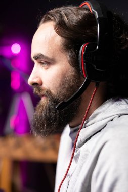 Stüdyodaki flamalar online izleyiciler için yayınlanıyor, onlarla konuşuyor, yaklaşan esport yarışmaları için stratejisini sunuyor. Oyuncu karanlık oturma odasından yayın yapıyor, izleyicilerle sohbet ediyor.