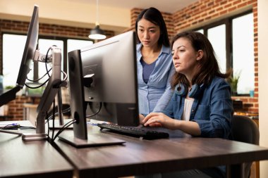 Yaratıcı ajans kadın profesyonelleri, yenilikçi fikirler üretmek için üretim departmanında işbirliği yapıyorlar. Asyalı müteahhit ve Kafkas meslektaşı bilgisayar ekranına bakıyor, tasarımlarını inceliyor.