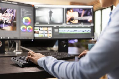 Video editörünün eli klavyede, gelişmiş yazılımları film görüntülerini rafine etmek için kullanıyor. Çoklu monitörle çalışan profesyonel film yapımcısı, sinema kalitesini artırmak için film çerçevelerini ayarlıyor.