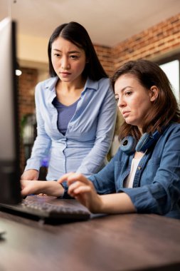 Modern ofisteki iki farklı kadın yaratıcı bir tartışmaya giriştiler, biri klavyede yazarken diğeri ekrandaki işi inceliyor. Bir proje üzerinde çalışan Asyalı ve Kafkasyalı meslektaşlar.