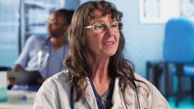 Kadın doktor, rutin kontroller için bir erkek hastayı muayene ediyor klinikteki tedavi planı hakkında konuşuyor. Uzman, sigorta konusunda sağlık hizmetleri sunar. Kamera B.