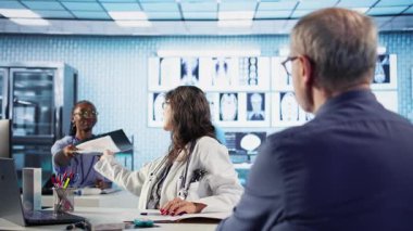 Kontrol sırasında doktorla teşhis sonuçlarını ve iyileşme planını tartışan yaşlı bir hasta. Laboratuvar sonuçlarını almak için ileri teknoloji kullanıyor. Sağlık sigortasında hasta bakımı. Kamera A.