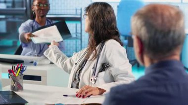 Kontrol sırasında doktorla teşhis sonuçlarını ve iyileşme planını tartışan yaşlı bir hasta. Laboratuvar sonuçlarını almak için ileri teknoloji kullanıyor. Sağlık sigortasında hasta bakımı. Kamera B.