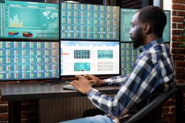 Afrika kökenli Amerikalı bir adam geceleri ticaret masasında çalışıyor. Forx çizelgelerini birden fazla monitörden izliyor. Tuğla duvar ofisinde geç saatlere kadar çalışan siyah erkek çalışanlar borsa büyümesini gerçek zamanlı gözden geçiriyorlar..