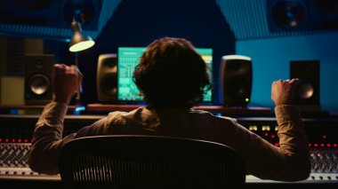Yetenekli ses tasarımcısı kendi müziğinden zevk alıyor. Kontrol odasında karışık konsol yaratıyor. Yeni parçasından memnun. Ses uzmanı stüdyoda düğmeli ve kaydıraklı melodileri düzenliyor. Kamera B.