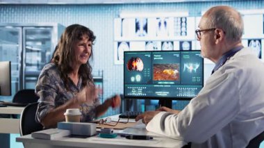 Şiddetli migrenle mücadele eden ve ilaç isteyen yaşlı bir kadın, doktor sağlık kontrolünde ağrıyı azaltmak için güçlü ağrı kesiciler içeren bir iyileşme planı hazırlıyor. Kamera A.