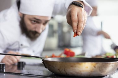 Kesinlik ve orijinallik, bir restoranın mutfağında çalışarak sobanın üzerine kesilmiş sebze ekliyor. Taze ürünlerle profesyonel aşçılık sanatı, gıda hazırlığı.