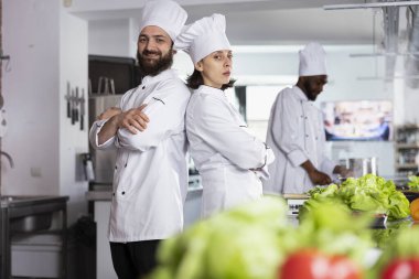 Mutfakta gurme yemekleri pişiren ve malzemeleri dikkatlice hazırlayan aşçılık uzmanları. Üniformalı ve şapkalı şefler en iyi gastronomi tekniklerini geliştiriyor..
