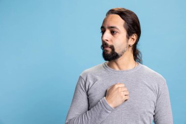 Stresli, endişeli, utangaç ve güvensiz bir adam endişeli düşüncelerle boğulmuş, mutsuz bir insan mavi arka plana karşı. Gözlerinde korku ve panik olan genç adam, ıssız..