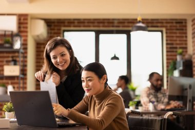 Tekerlekli sandalye kullanıcısı da dahil olmak üzere çeşitli iş kadınları bir ofis masasının etrafında toplanarak, yeni başlayan şirketlerin mali verilerini analiz ediyorlar. Modern ofiste pazarlama planları yapan kadın girişimciler..