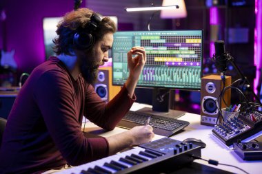 Besteci kendi stüdyosunda yeni bir şarkı yaratmak için notlar alıyor, konsol ve mikrofon karışımı müzik endüstrisi üzerine notalar ve şarkı sözleri yazıyor..