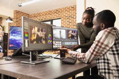 Tuğla duvar çalışma alanındaki film çerçevesi kalitesini arttırmak için çoklu monitör düzeneği kullanan yetenekli bir yaratıcı ekip. Kadın takım arkadaşı olarak masa başında çalışan profesyonel erkek editör görüntülerin geliştirilmesinde yardımcı oluyor.