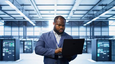 Veri merkezindeki bilgisayar bilimcisi, hata nedenlerini tespit etmek için dizüstü bilgisayardaki tanısal araçları ve sistem izleme yazılımını kullanıyor. Bilgi İşlem Uzmanı Sunucu Çiftliği Onarım ekipmanları, Kamera B