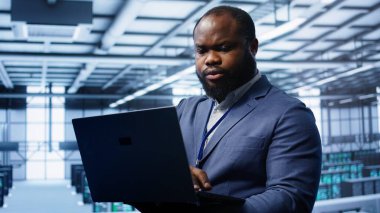 Yüksek teknoloji tesislerindeki bilgisayar bilimcileri, sunucu kabinelerini etkileyen ağ sorunlarını gidermek için dizüstü bilgisayar kullanıyor. Bu da müşteri iletişiminin kötü olmasına neden oluyor. Kamera B: