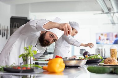 Hassasiyet ve yaratıcılık, şef sebzeleri bir restoranın mutfağında çalışırken ocağın üzerine serpiştirirken parlıyor. Taze sebzeli profesyonel mutfak sanatı, yemek hazırlığı..