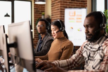 Afrika kökenli Amerikalı meslektaşlarıyla birlikte çalışan kadın çalışanların seçici odak noktası. Uzaktan müvekkil desteği sağlıyorlar. Masaüstü bilgisayarında müşteri geribildirimini analiz eden Asyalı kadın.