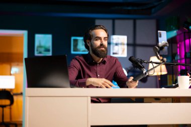 ASMR sanatçısı özçekim çubuğunda kaliteli mikrofon ve akıllı telefon kullanarak stres karşıtı videolar çekiyor, fısıltı sesleri çıkarıyor. Profesyonel mikrofon ve telefon kamerasıyla rahatlama içeriğini kaydeden adam.