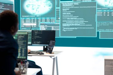 Siber savunma uzmanı hükümet merkezindeki büyük ekranda siber güvenlik operasyonları ve dijital tehditlere odaklanan bilgileri inceliyor. Hacker siber suçlulara karşı koruma sağlıyor.