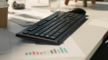 Parlak ofis ortamında analitik veri belgeleriyle dolu modern çalışma alanı ve saksı bitkileri. Ekranda gösterilen dijital istatistik çizelgeleriyle birlikte masadaki tablet, görüntüyü kapat