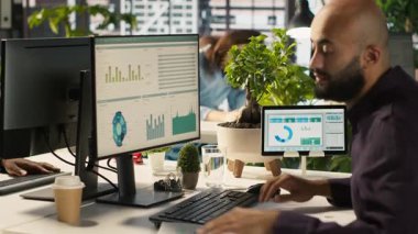 Ofis masasındaki masaüstü bilgisayarında dosya düzenleme, raporlar ve dosyalar güncelleniyor. İşçi masadaki bilgisayar ekranında veri tablolarını analiz ediyor, istatistiksel bilgileri yorumluyor, kamera A