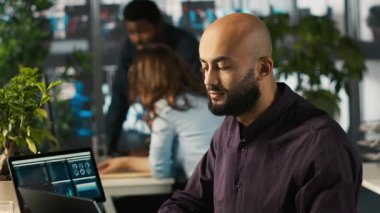 Ofisteki mutlu adam finansal grafikleri inceliyor, iyi performans göstergeleri gördükten sonra memnun oldu. Pozitif KPI ve veri eğilimlerini kutlayan neşeli bir çalışan, kamera A