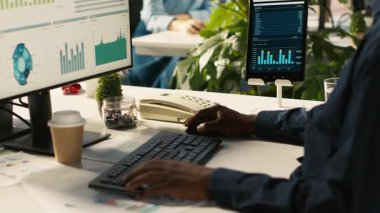 Ofisteki işçileri müşterilerle konuşmak için sabit telefonu kullanarak kapatın. İş yerinde çalışan Afrikalı Amerikalı bir çalışan çağrı sırasında iş ortağıyla tartışıyor, performans ölçümlerini analiz ediyor, kamera A