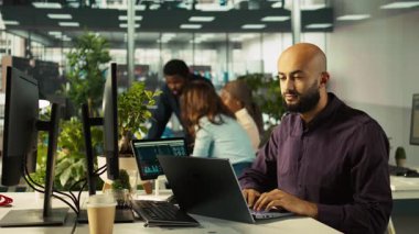 Ofisteki mutlu adam finansal grafikleri inceliyor, iyi performans göstergeleri gördükten sonra memnun oldu. Pozitif KPI ve veri eğilimlerini kutlayan neşeli bir çalışan, kamera B