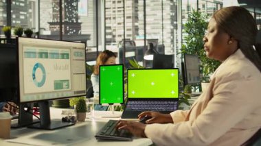 Ofis masasında bilgisayardaki belgeleri düzenleyen çalışanın yanında izole ekran bilgisayarı ve tablet var. Veri tablolarını analiz eden, istatistiksel bilgileri yorumlayan işçinin yanındaki krom anahtar cihazlar, kamera B